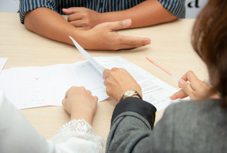 Corporate AI training quotation checklist Malaysia: two people reviewing a training proposal at a meeting table