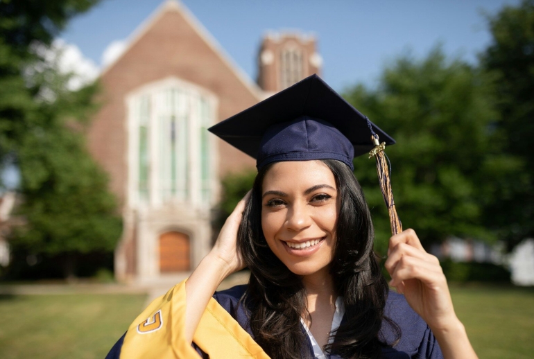 a woman in a cap and gown holding a diploma